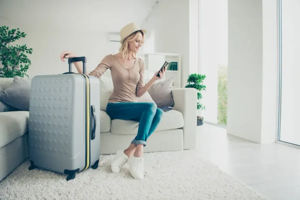 woman using phone while holding suitcase